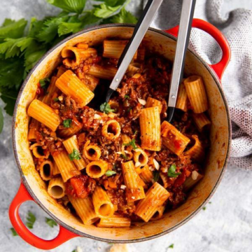 roter gusseiserner Topf, gefüllt mit Rigatoni in Bolognese Sauce