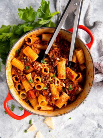 roter gusseiserner Topf, gefüllt mit Rigatoni in Bolognese Sauce