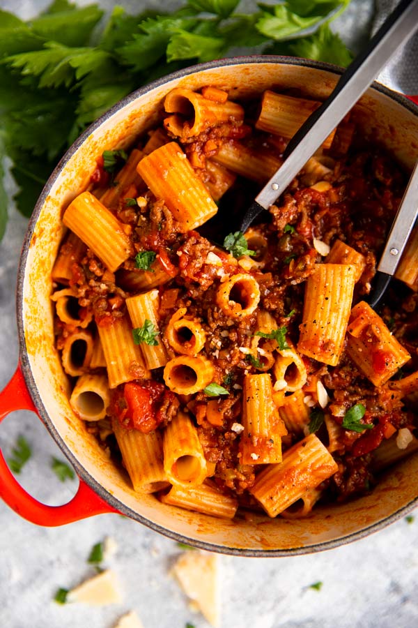 roter gusseiserner topf mit rigatoni bolognese