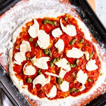 ungebackene Pizza auf einem Blech mit Silikon-Backmatte