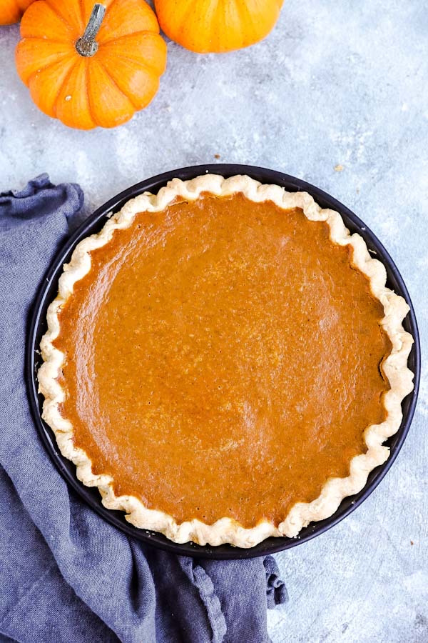 Pumpkin Pie auf einem Tisch mit einem schwarzen Tuch und frischen Kürbissen