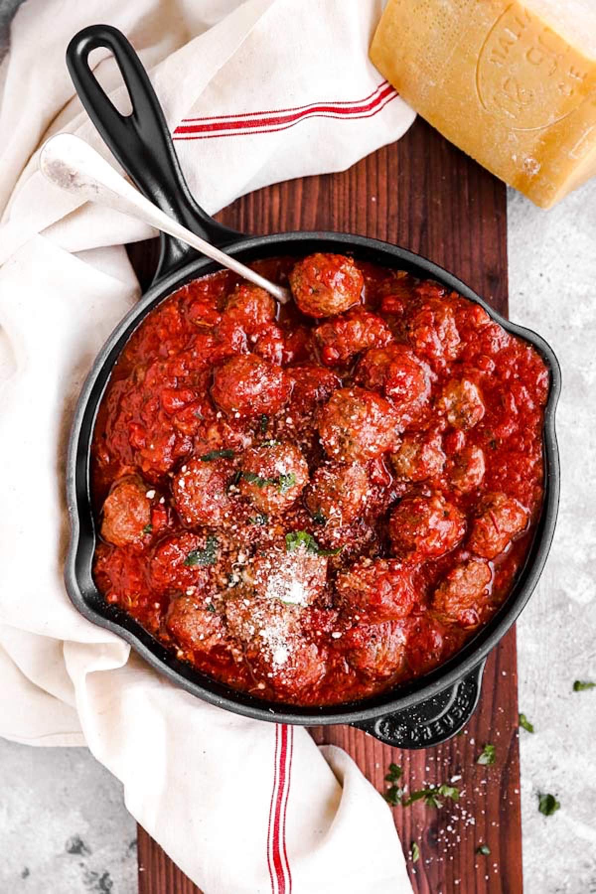 Pfanne mit Hackbällchen in Tomatensauce auf einem Holzbrett