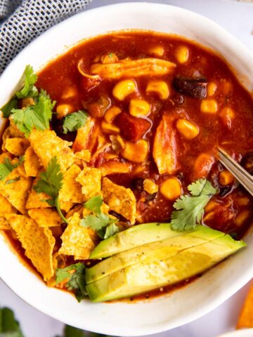 schale mit Mexikanischer Hühnersuppe, Tortilla Chips und Avocado