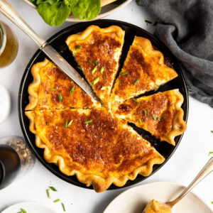 geschnittene Quiche Lorraine von oben auf einem Tisch mit Salat und Tellern