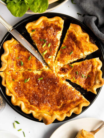 geschnittene Quiche Lorraine von oben auf einem Tisch mit Salat und Tellern