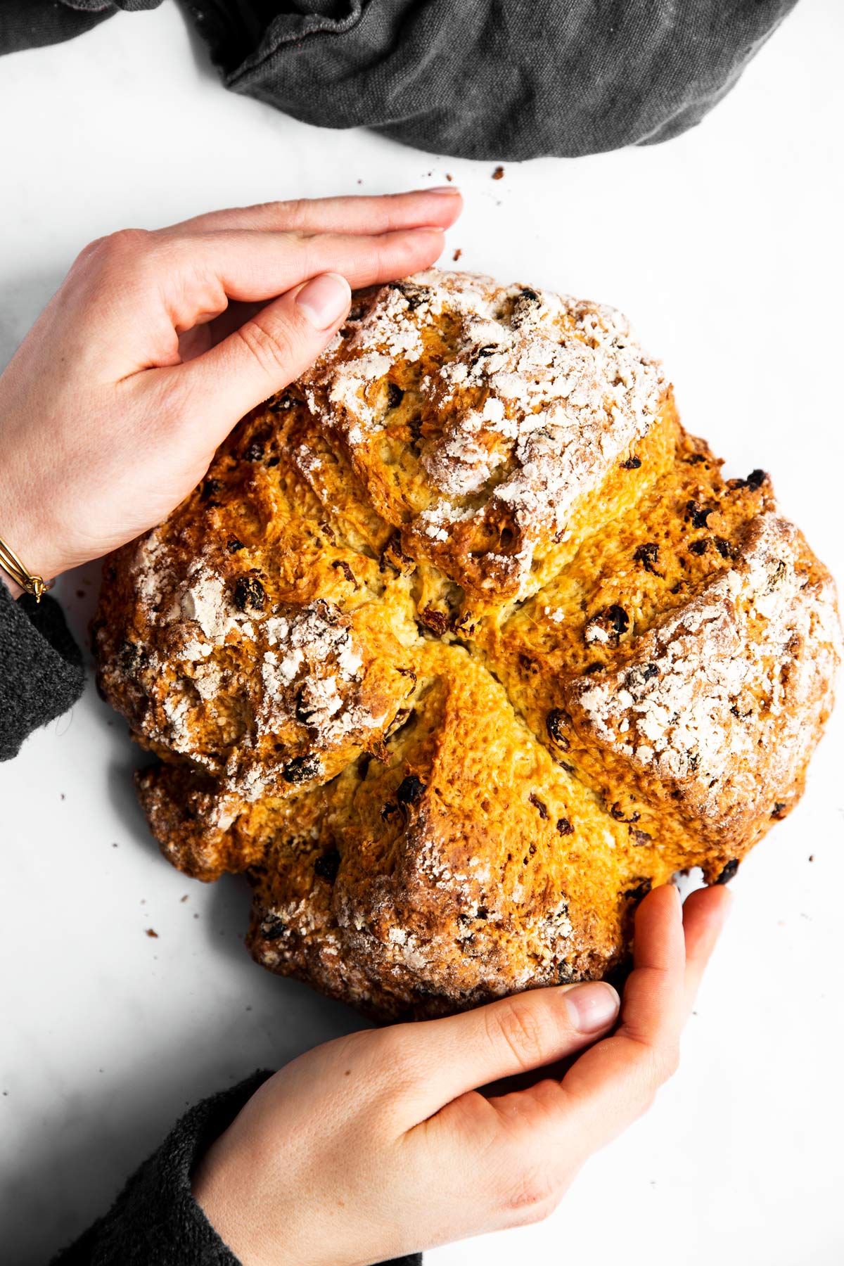 Rosinenbrot von Oben, wird von zwei Händen festgehalten