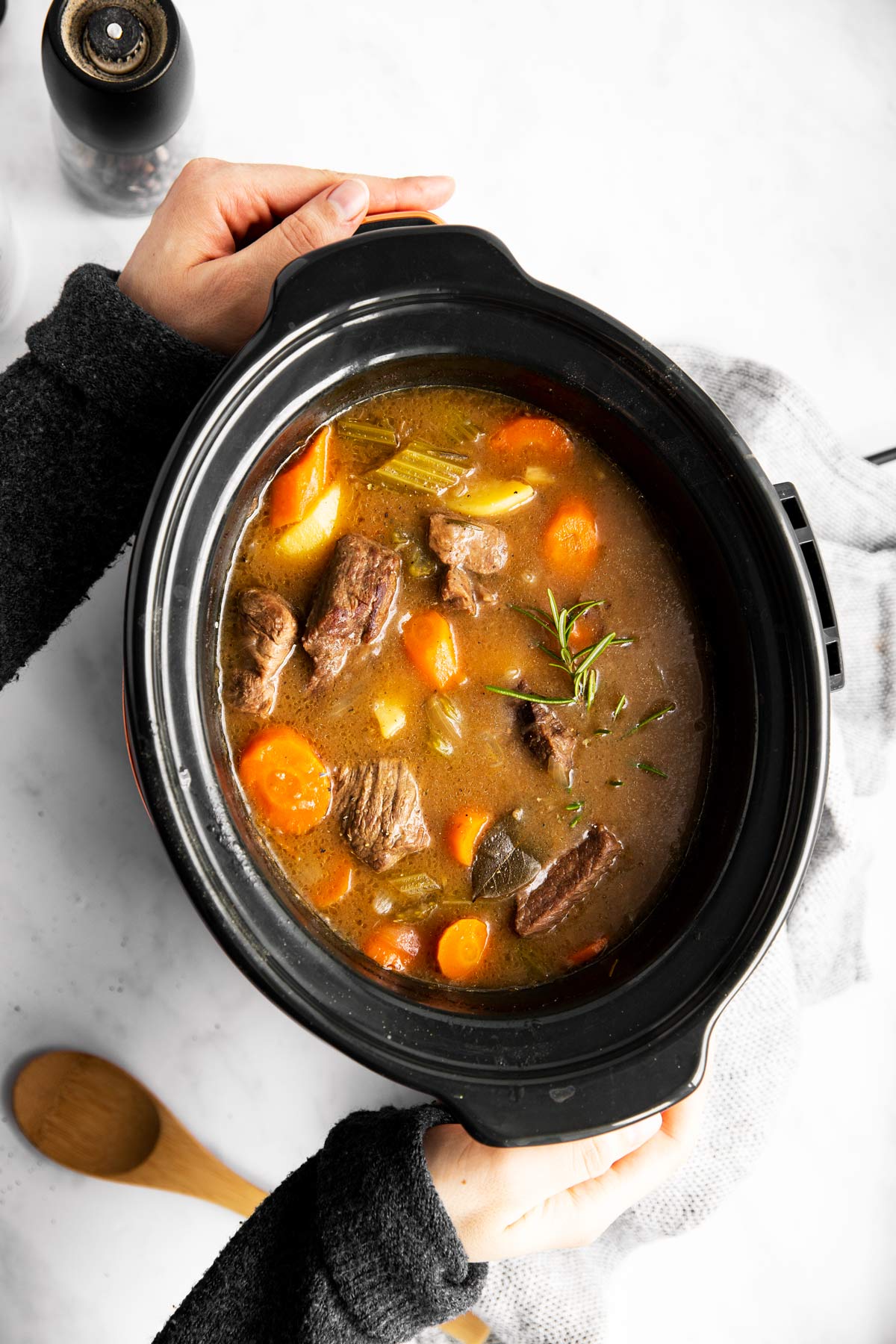 Frau hält Slow Cooker mit Gulasch