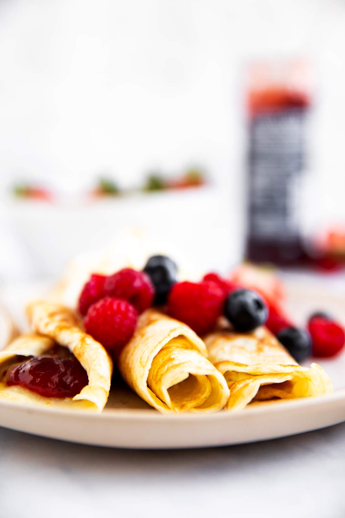 Teller mit Pfannkuchen mit Beeren und Marmelade im Hintergrund