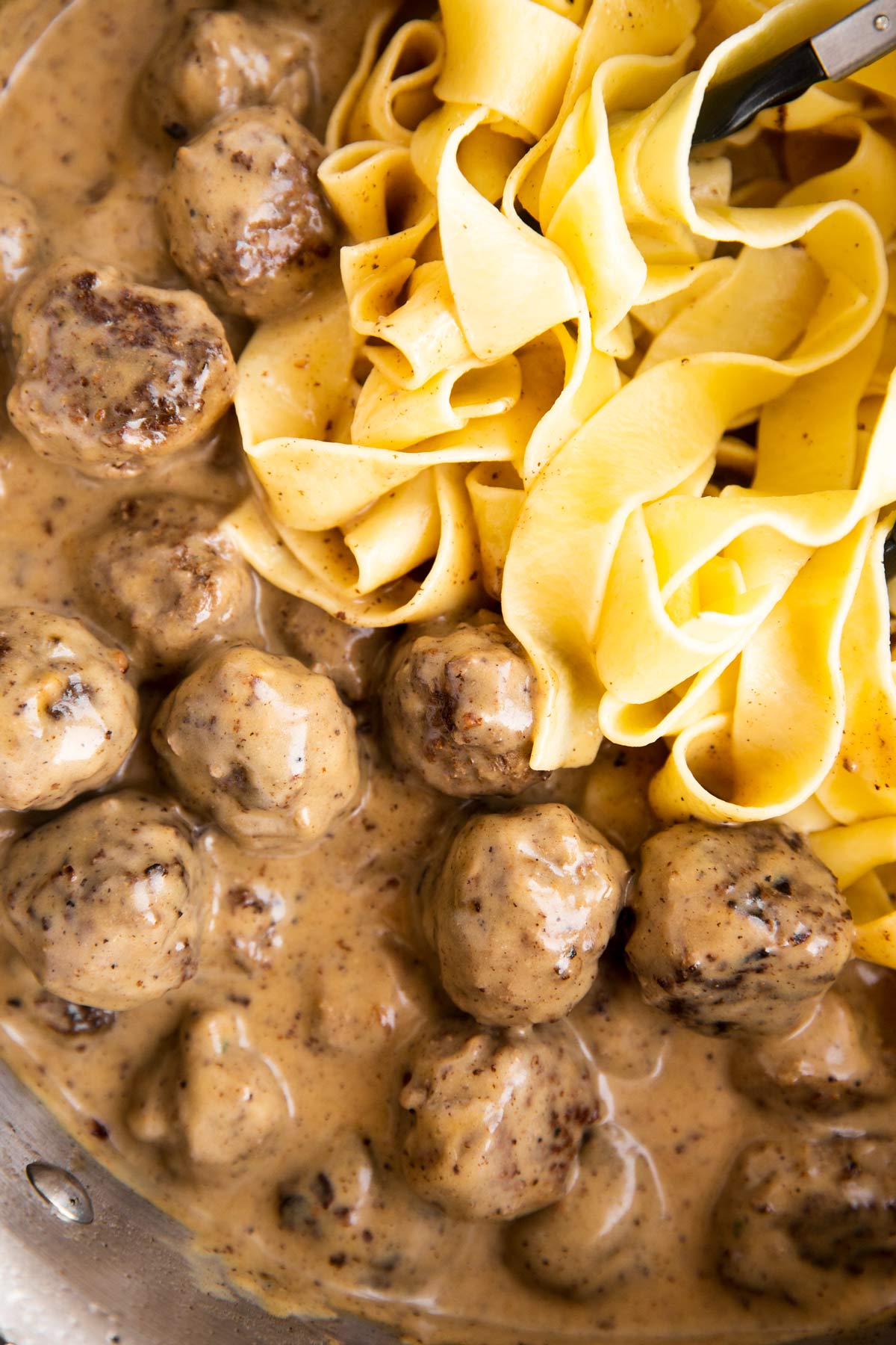 Nahaufnahme von schwedischen Fleischbällchen in Köttbullar Sauce neben Bandnudeln