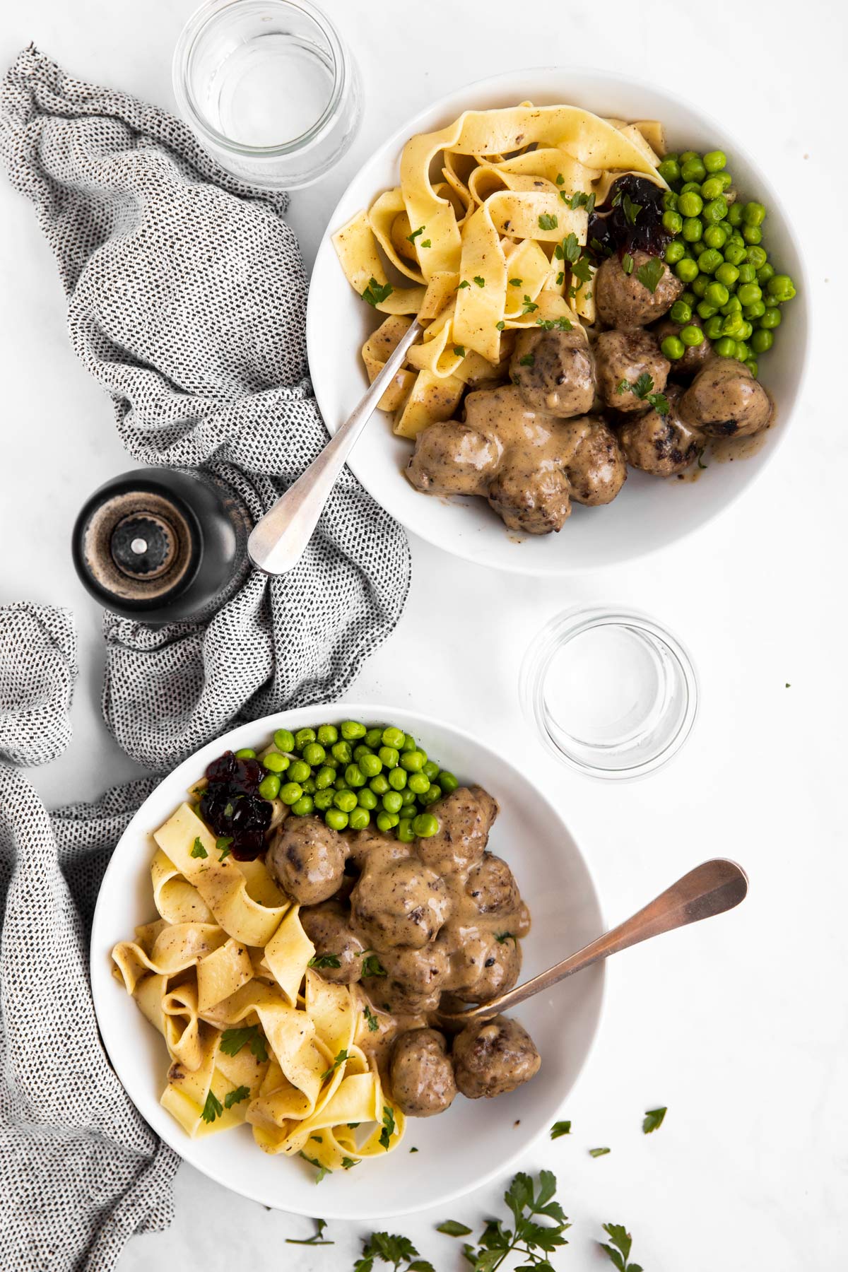 Blick von Oben auf zwei Teller mit Köttbullar, Nudeln und Erbsen