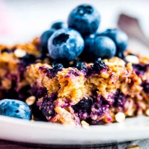 Stück von Baked Oatmeal auf Teller mit frischen Blaubeeren