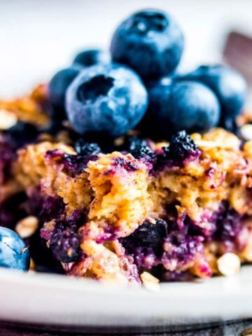 Stück von Baked Oatmeal auf Teller mit frischen Blaubeeren