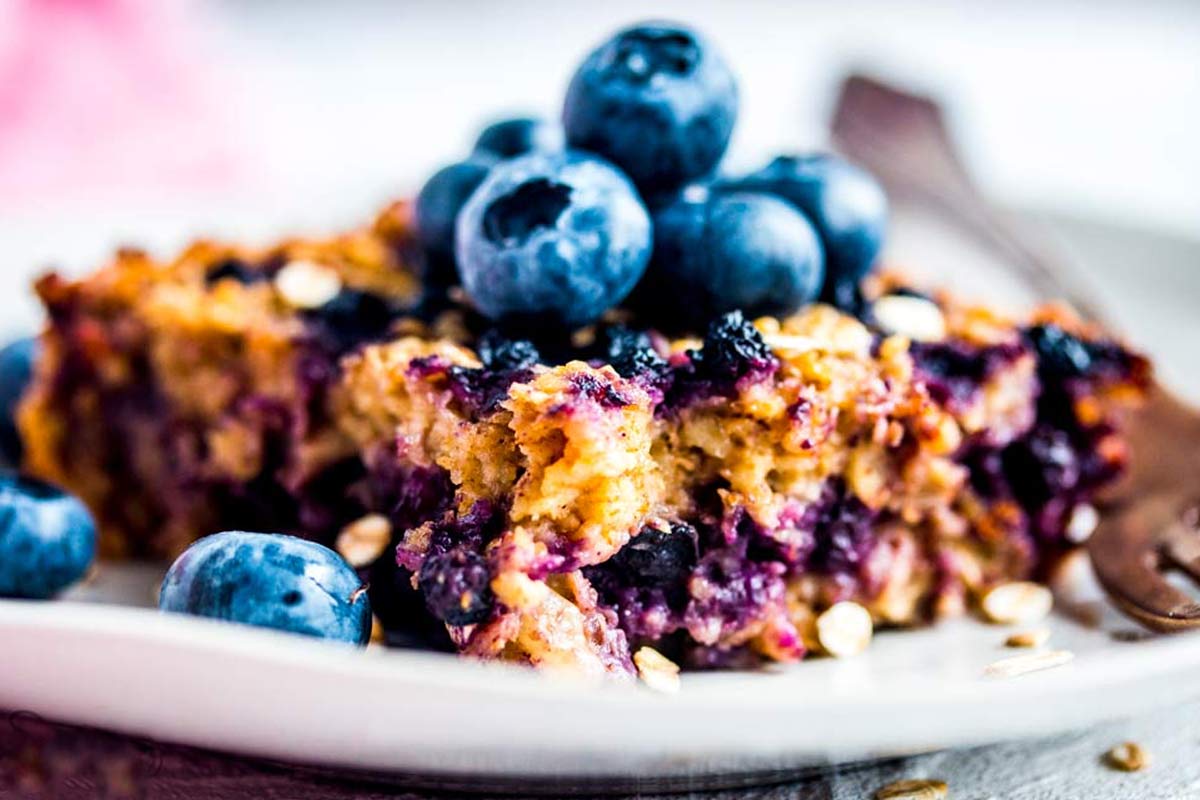 Stück von Baked Oatmeal auf Teller mit frischen Blaubeeren