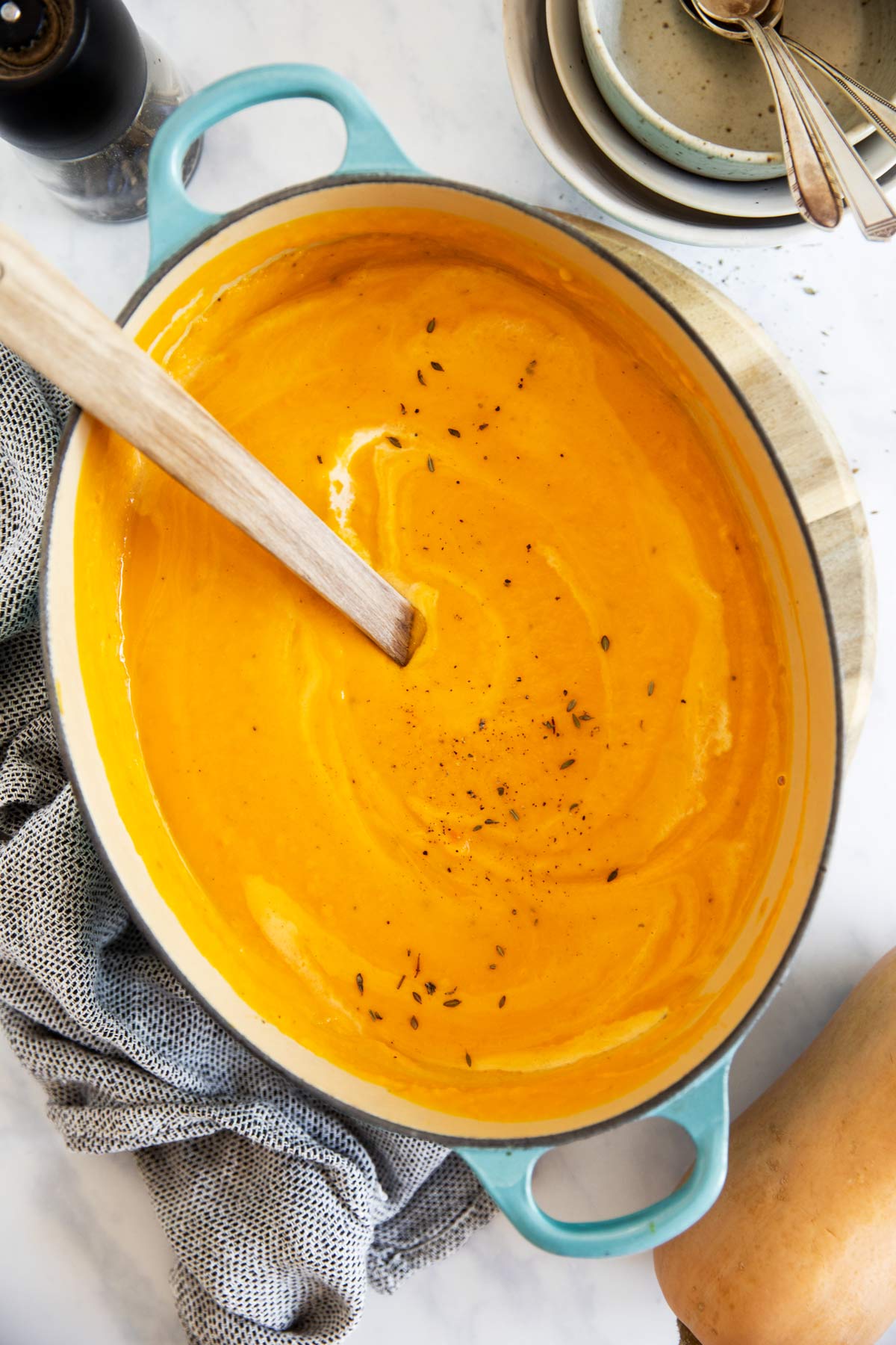 türkisfarbener Topf mit Butternuss Kürbissuppe auf hellem Untergrund