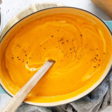 türkisfarbener Topf mit Butternuss Kürbissuppe auf hellem Untergrund