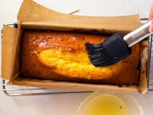 Ansicht von Oben auf gebackenen Zitronenkuchen in Kastenform der gerade getränkt wird